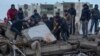 Un grupo de personas busca entre los escombros de un edificio a sobrevivientes tras un sismo, en Adana, Turquía, el lunes 6 de febrero de 2023. (AP Foto/Khalil Hamra)
