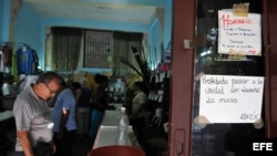 Varias personas observan productos dentro de una tienda, donde se puede ver un cartel alusivo al control sanitario hoy, martes 15 de enero del 2013, en la capital cubana. El Gobierno de Cuba informó de que se han confirmado hasta ahora 51 casos de cólera