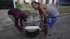 Residentes llevan una olla de caldosa para compartir con los vecinos después del paso del huracán Rafael por La Habana, el 7 de noviembre de 2024. (Foto AP/Ariel Ley)