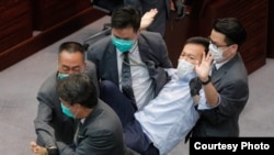 Los guardias de seguridad arrastran al legislador pro democracia Ray Chan durante una reunión legislativa el 8 de mayo de 2020 en Hong Kong.