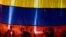 La silueta de tres activistas en una bandera de Venezuela.